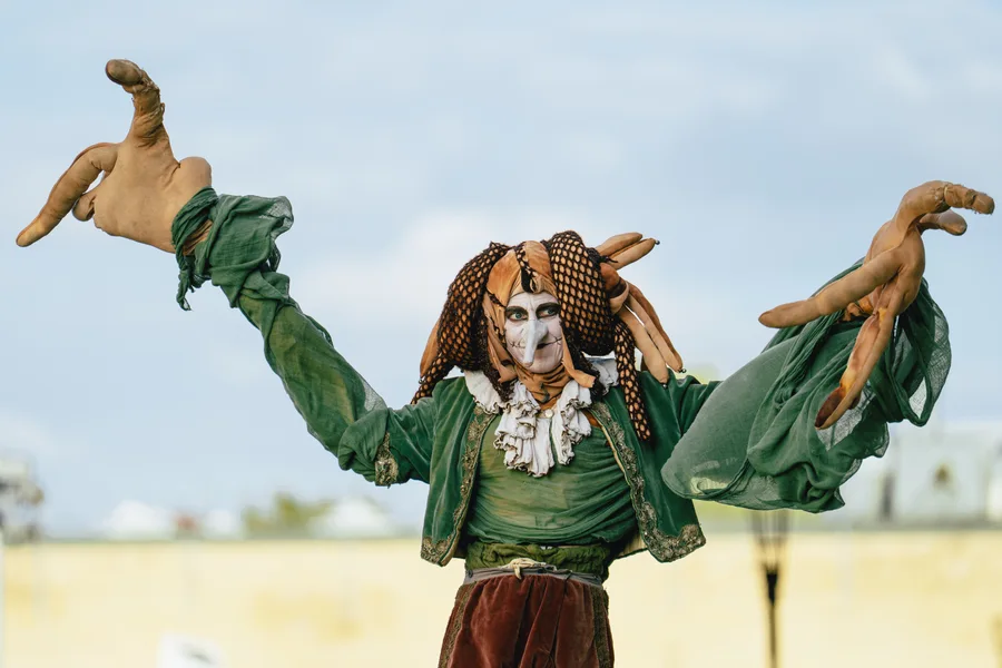 A costumed performer extends oversized hands towards the camera.